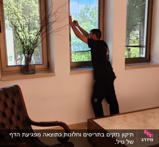 אדם מתקין תריסים בחלון בבית